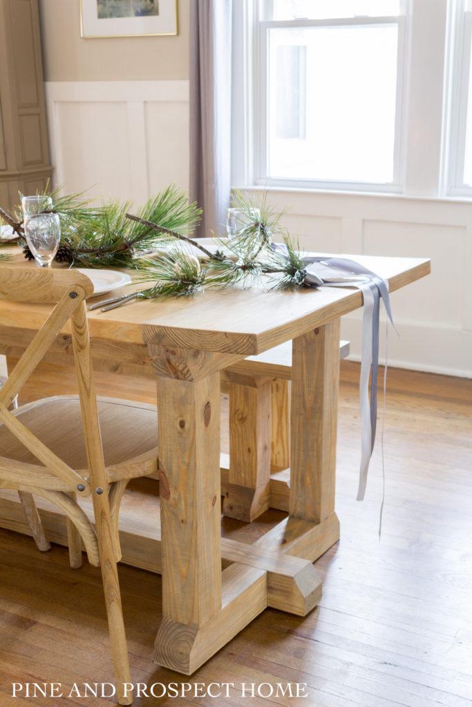 DIY Farmhouse table decorated with ribbon and pine branches for Christmas