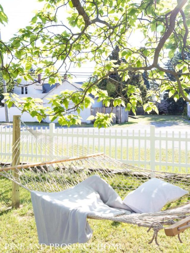 ambiance, backyard, beautiful, beautiful backyard, beauty, borders, chairs, cottage, cottage home, cottage home exterior, cottage style, diy, diy outdoor projects, diy projects, english cottage style, fence, fire, fire pit, flower beds, flower boxes, flower garden, flowers, gardens, hammock, Home exterior, inspiration, lighting, low maintenance plants, natural, neutral, outdoor dining, outdoor seating, outdoor space, Outdoors, patio, pea gravel patio, Plants, rock border, rocks, stone, stone border, string lights, vegetable garden, white picket fence, wood, wood fence