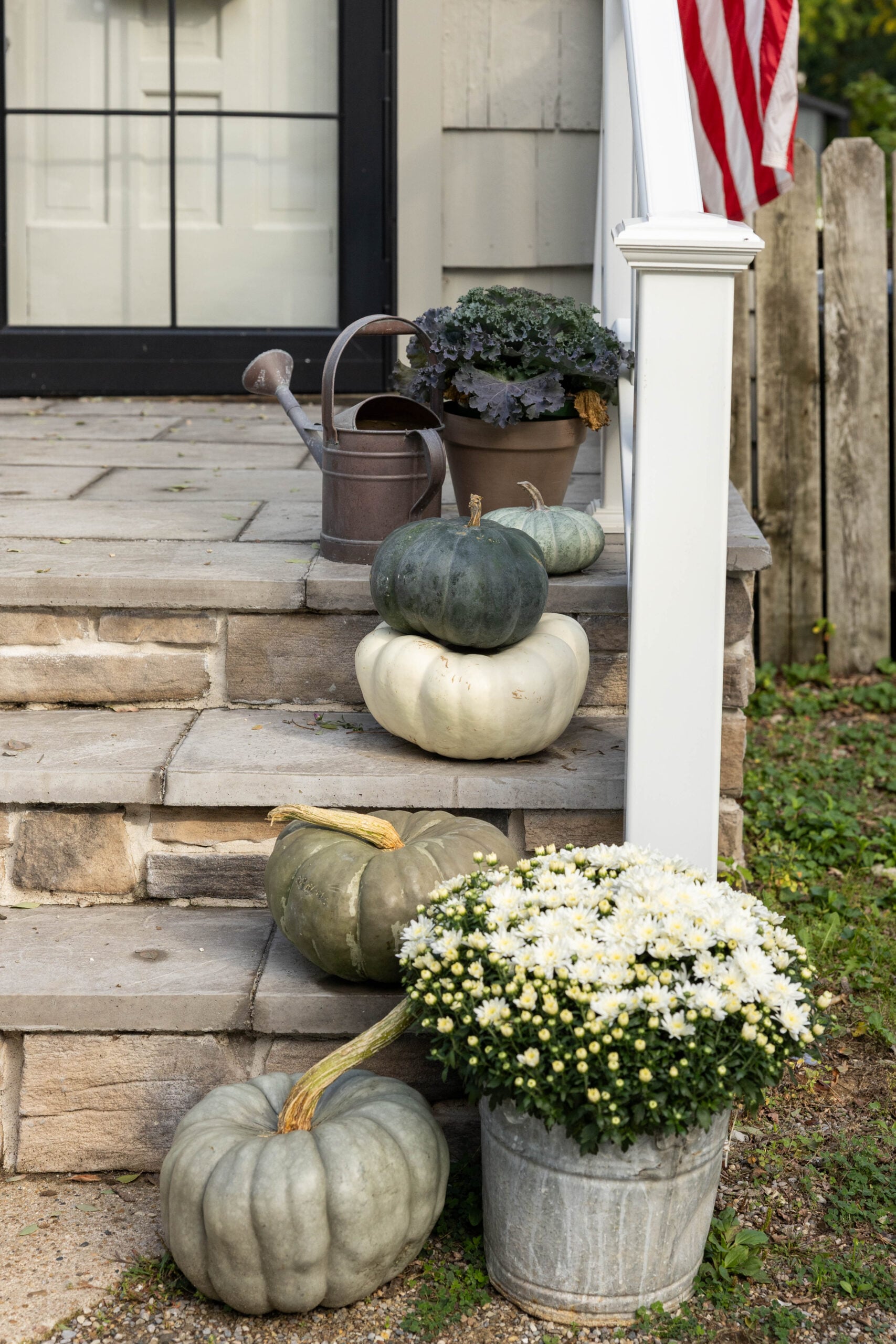 Fall porch decor using mums, pumpkins and watering can